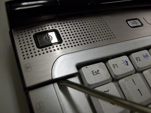Picture of flathead screwdriver being inserted to pry up plastic bar